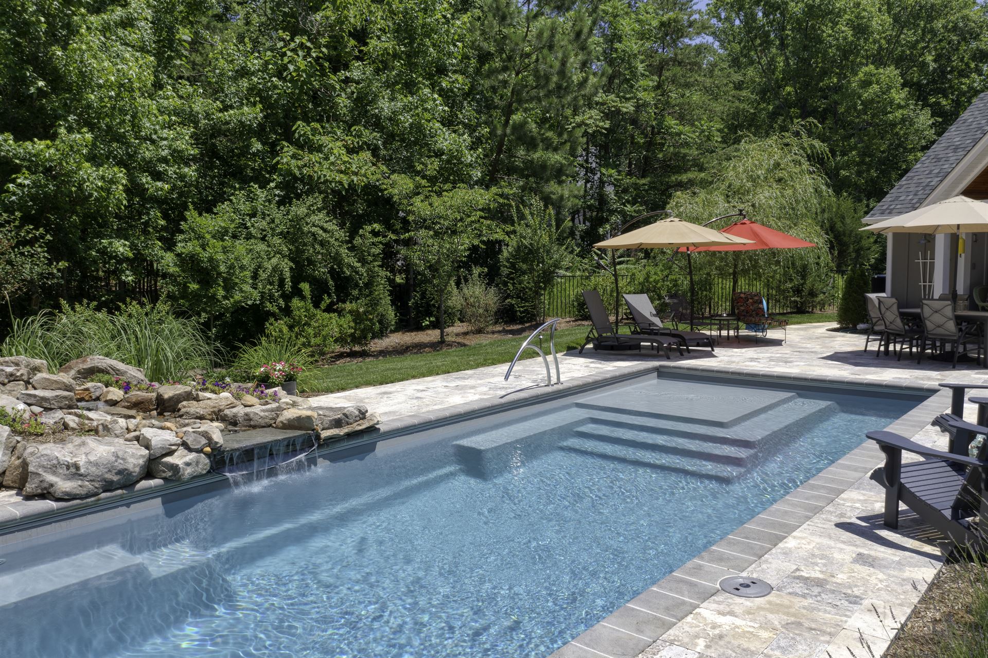 River Pools M35 in Diamond color with a cascade, natural stone patio, and concrete paver coping