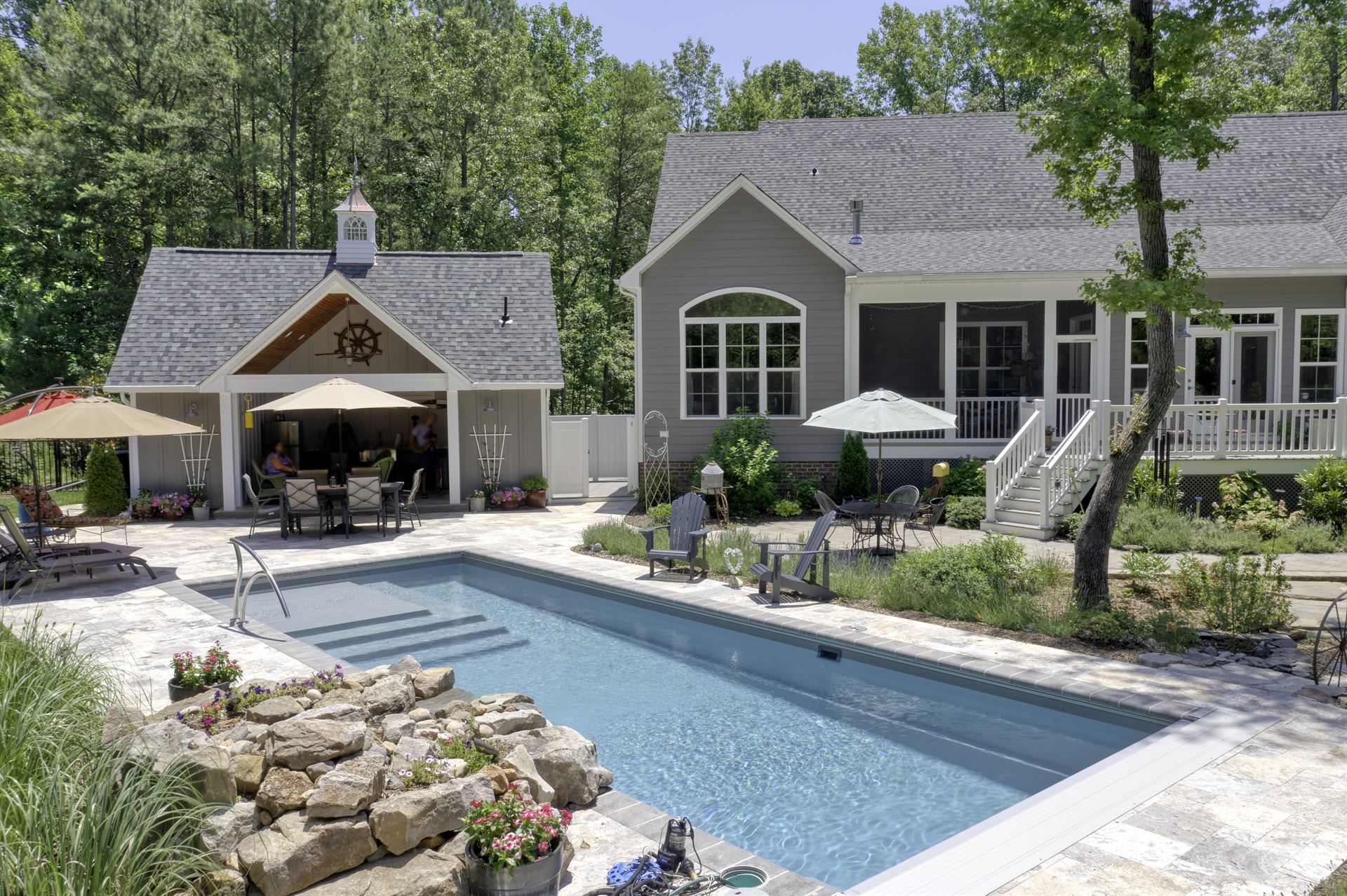 River Pools M35 in Granite Gray with a cascade, natural stone patio, and concrete paver coping