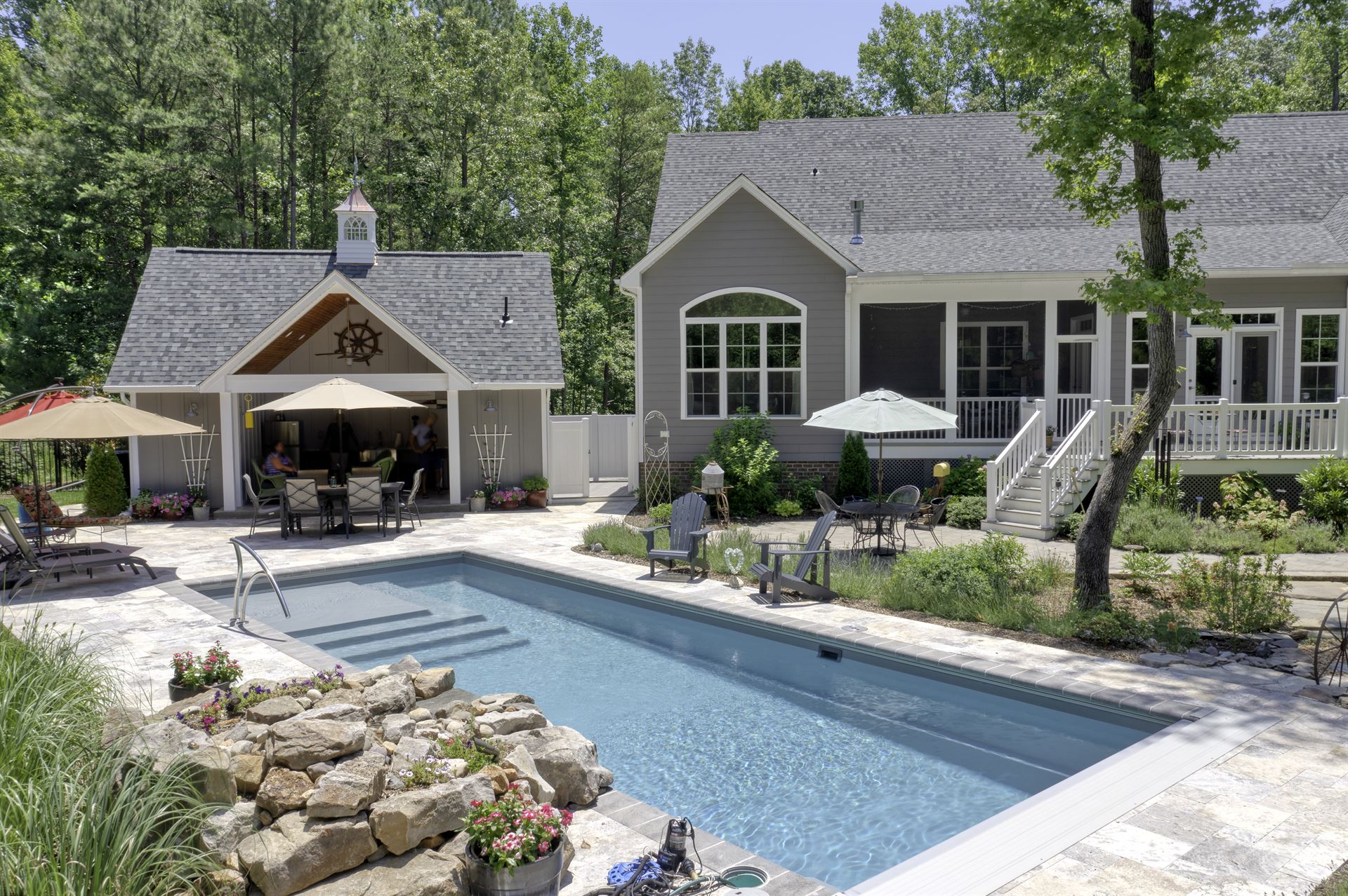 River Pools M35 in Diamond color with a cascade, natural stone patio, and concrete paver coping