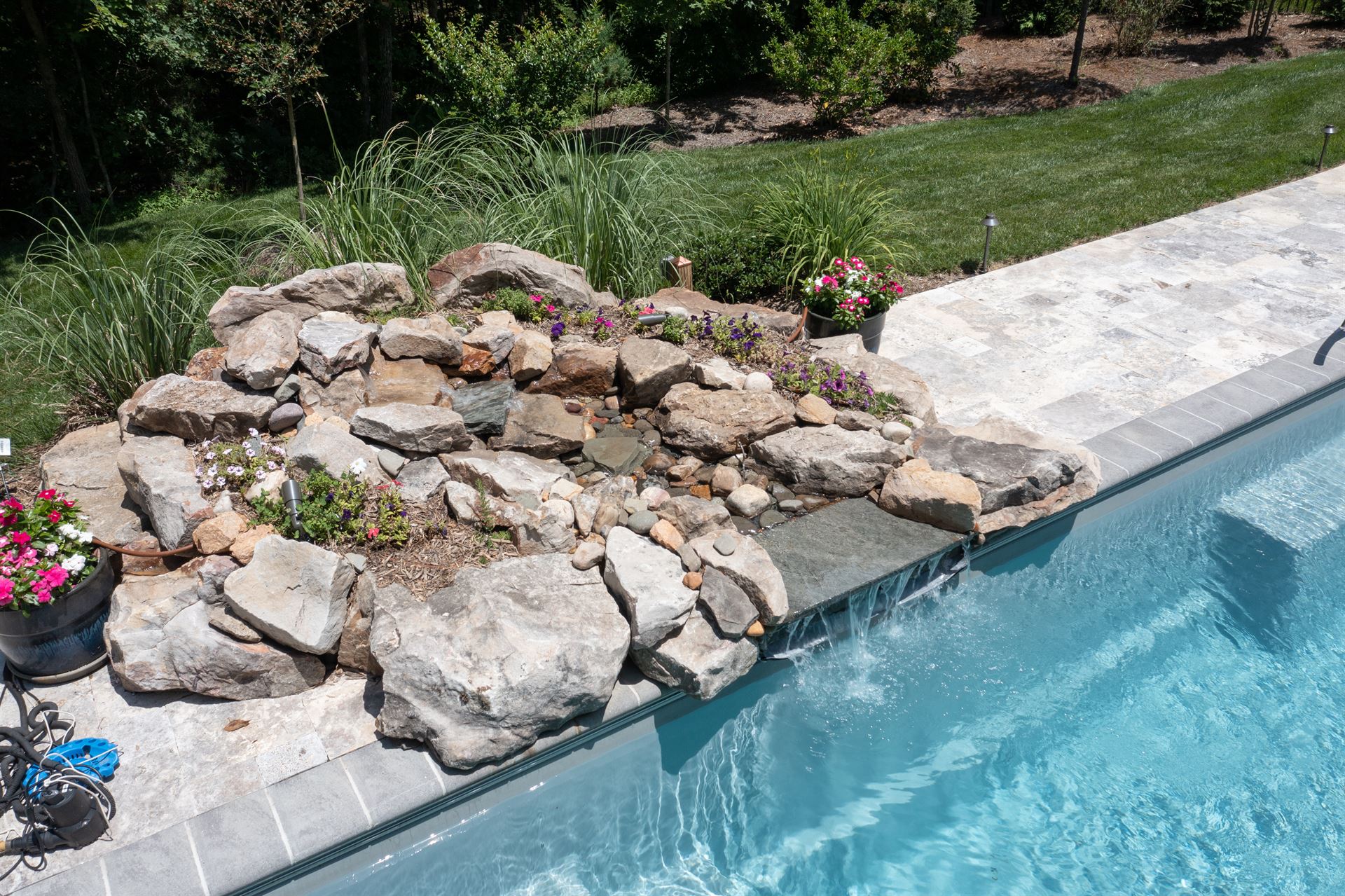 River Pools M35 in Diamond color with a cascade, natural stone patio, and concrete paver coping