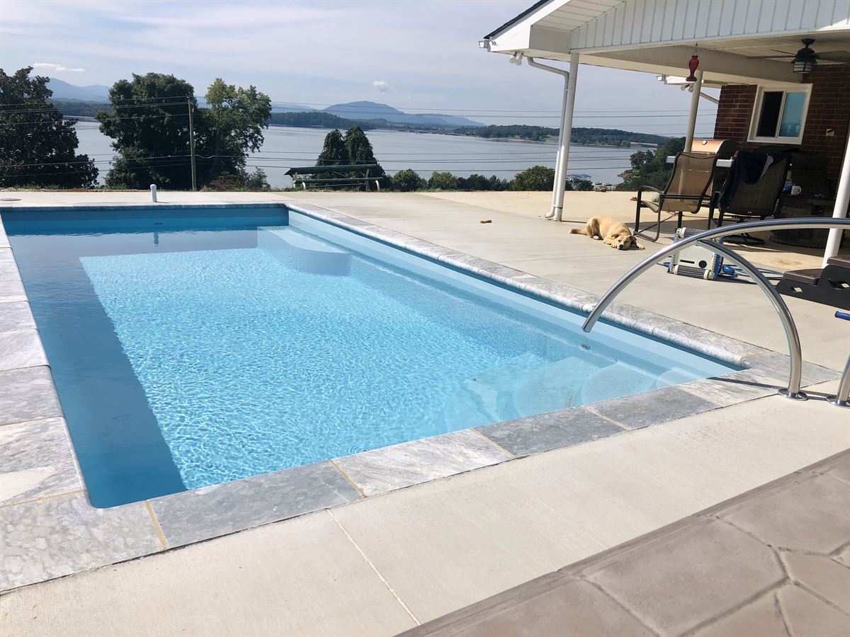 R24 pool in Caribbean with travertine coping and brushed concrete decking