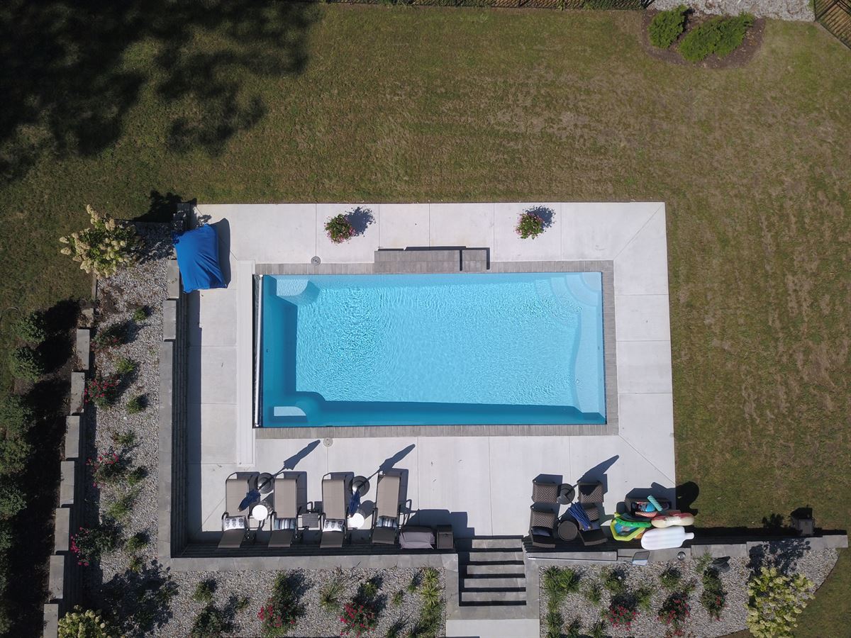 R32 pool in Caribbean with paver coping and brushed concrete decking featuring a cascade water feature