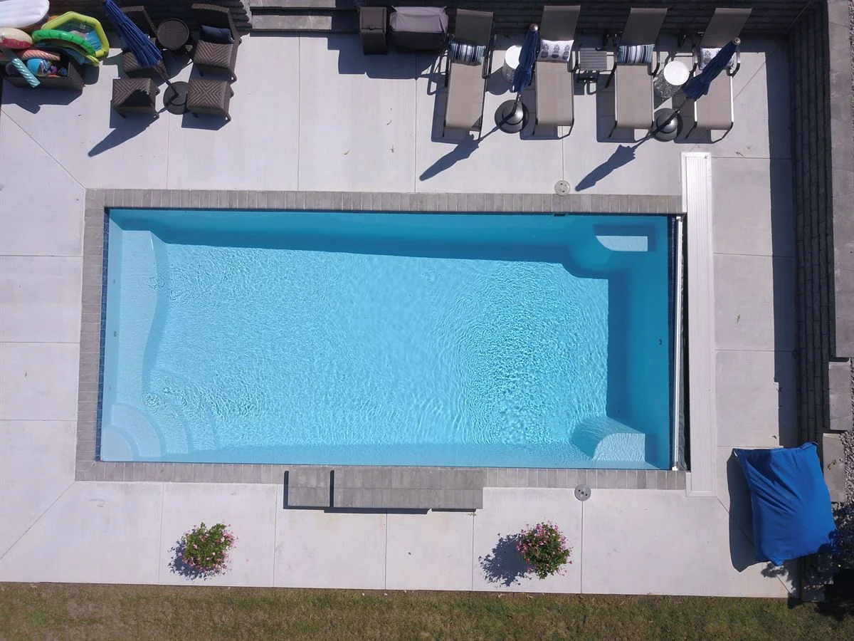 R32 pool in Caribbean with paver coping and brushed concrete decking featuring a cascade water feature