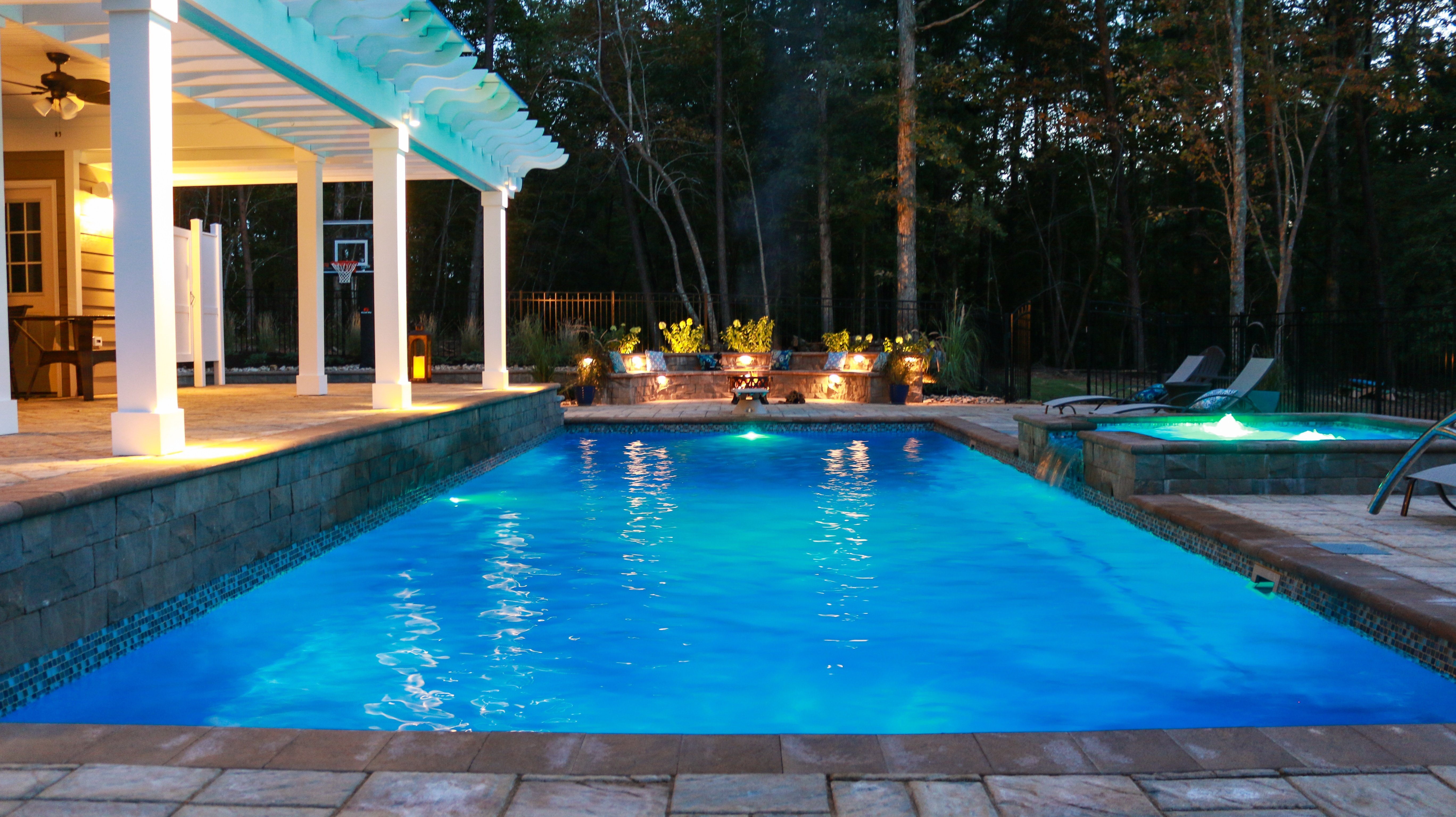 40 pool in maya blue color at night with pool lights and a tanning ledge with a spillway and bubblers